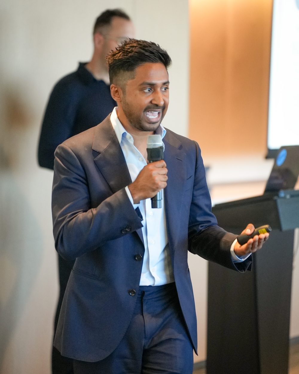 Redom Syed speaking on stage with a microphone